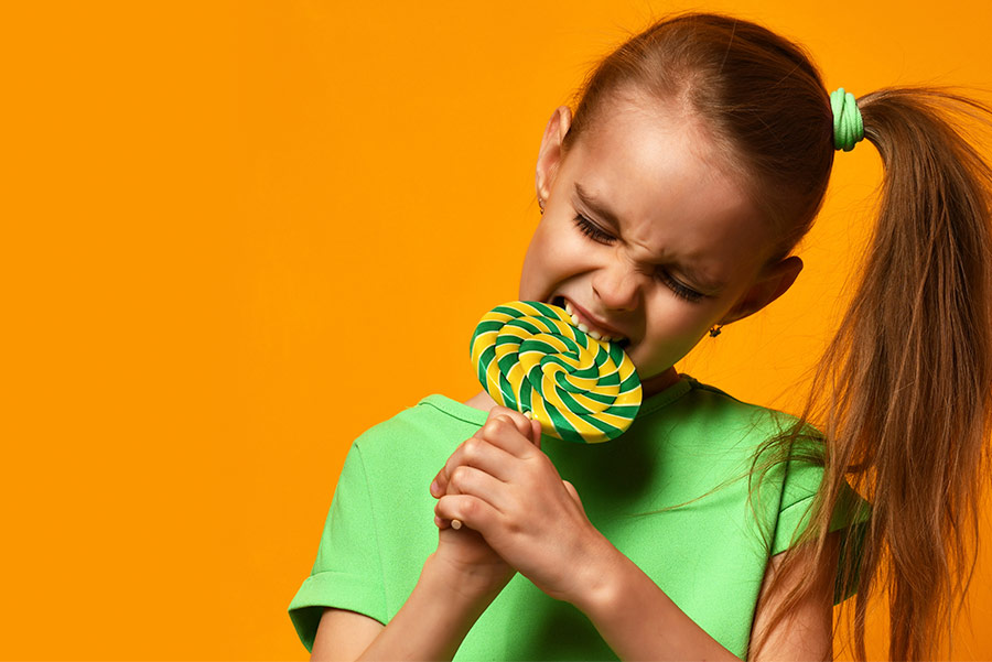 Niña mordiendo una piruleta de azúcar