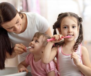 Niñas siguen consejos para lavarse bien los dientes.